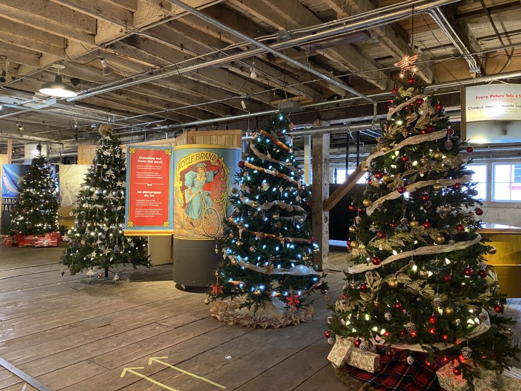 Four decorated Christmas trees on display inside historic cannery